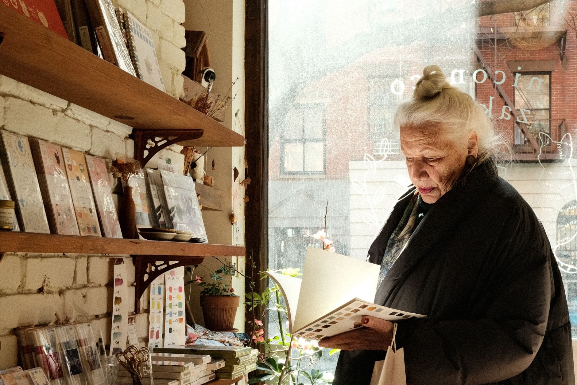 Senior woman reading in a cozy bookstore with sunlight streaming through the window